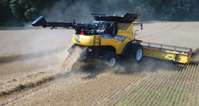 A 2024 New Holland CR Series Twin-Rotor combine harvesting grain in a field.
