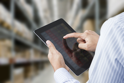 Close-up of a man in a blue and white striped shirt using a tablet to check his inventory.